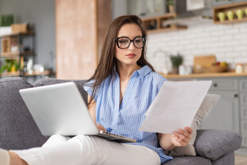 Woman sat in chair looking between computer and document